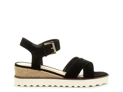 Black suede wedge sandal with ankle strap, gold buckle, jute trim, and white platform sole