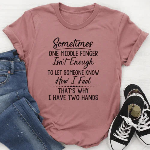 Mauve graphic tee with humorous quote, paired with jeans and black sneakers, flat lay
