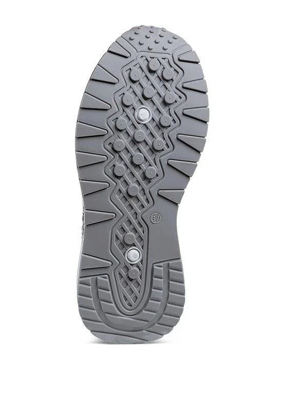 Gray athletic shoe sole with textured grip, circular studs, and zigzag tread pattern