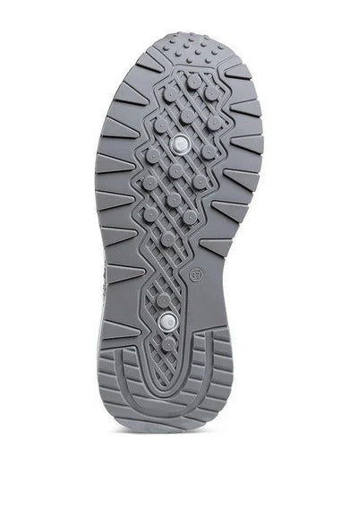 Gray athletic shoe sole with textured grip, circular studs, and zigzag tread pattern