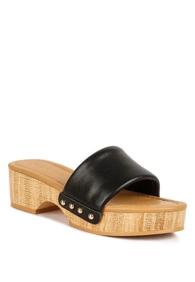 Women's black slide sandal with wide strap, wooden platform heel, and gold stud accents