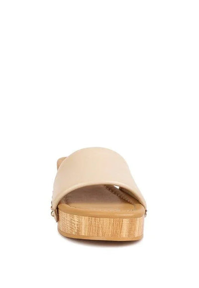 Beige slide sandal with wide strap and wooden platform sole, front view on white background