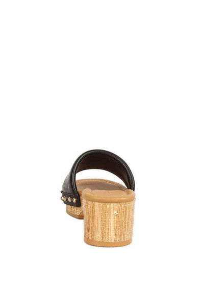 Black slide sandal with low wooden block heel and gold studs, rear view on white background