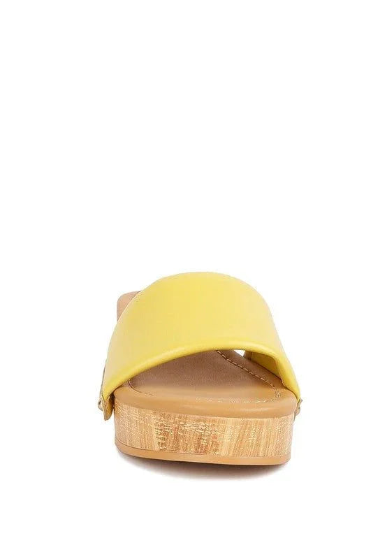 Yellow slide sandal with wide strap and cork-patterned sole on white background