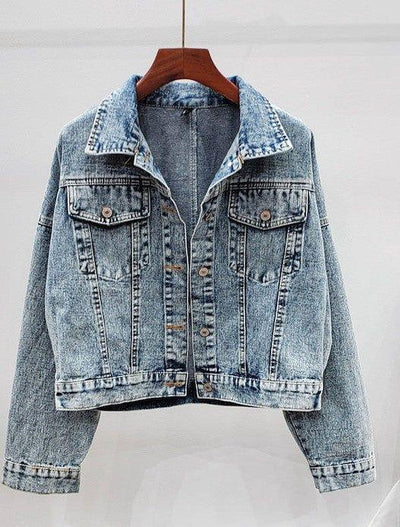 Light blue acid wash denim jacket with button front and chest pockets on hanger