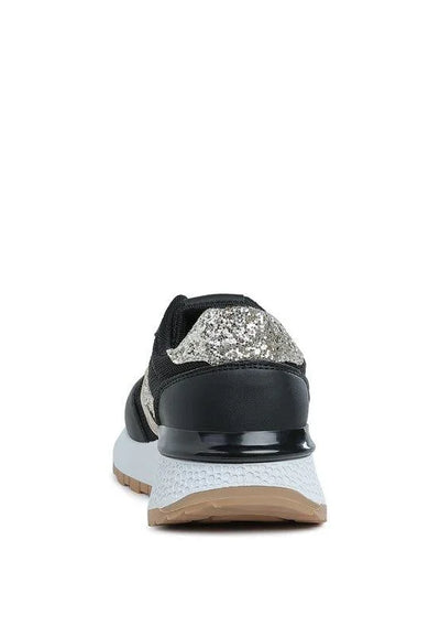 Black sneaker with silver glitter heel, white midsole, and gum sole, rear view