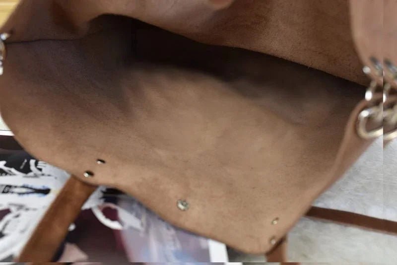 Open brown suede tote bag interior detail with metal rivets on a magazine background