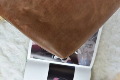 Brown leather furniture corner over open magazine on soft white rug