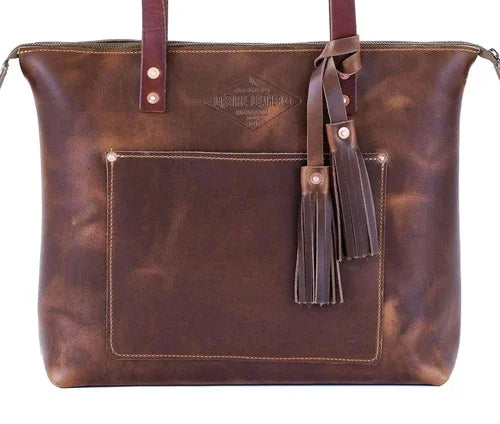 Brown leather tote bag with front pocket, tassel accents, and sturdy handles