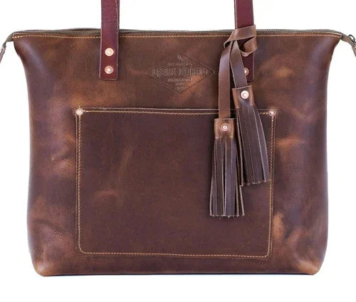 Brown leather tote bag with front pocket, tassels, and dual handles