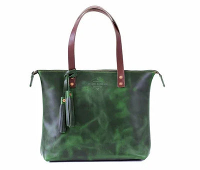 Emerald green leather tote bag with brown handles and tassel, front view on white background