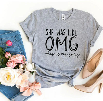 Gray graphic tee with 'She was like OMG this is my song' text, blue jeans, pink flowers, heels