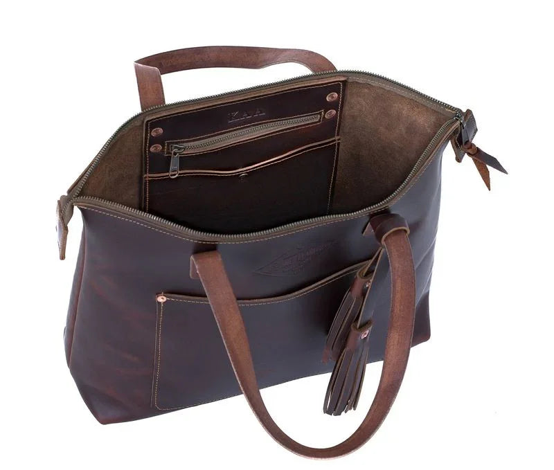 Brown leather tote bag with zipper, interior pockets, and tassel detail on handle