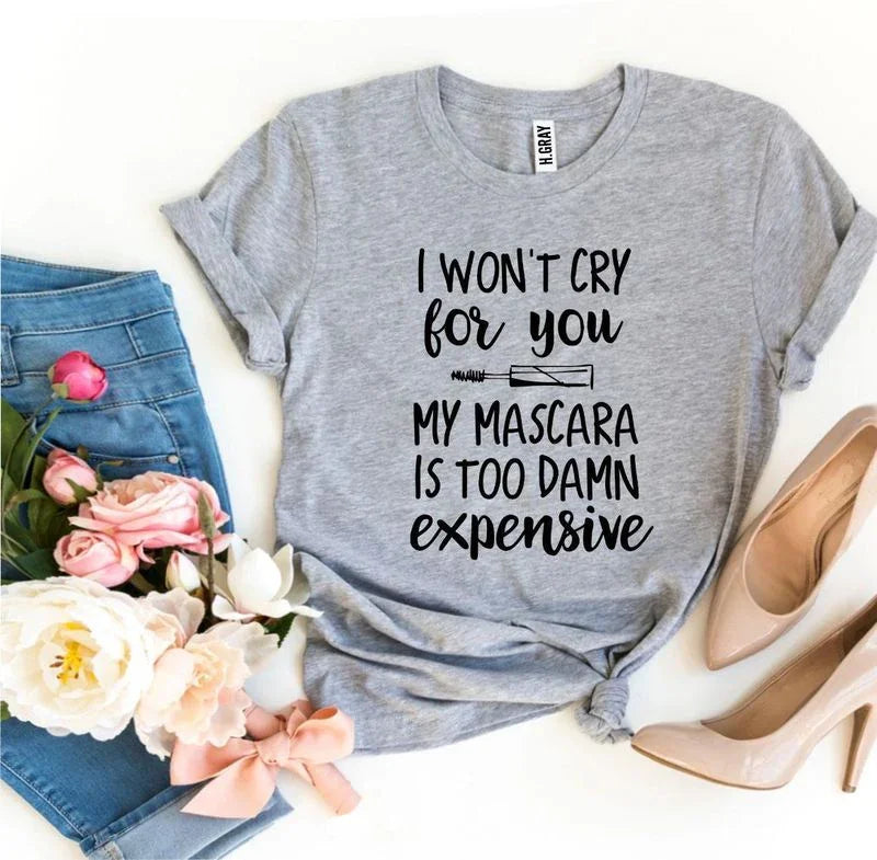 Grey graphic t-shirt with mascara quote, blue jeans, flowers, pink bow, and nude heels.
