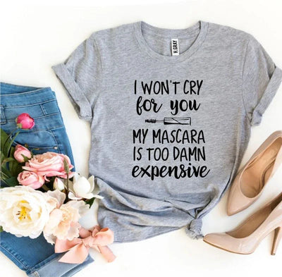 Grey graphic t-shirt with mascara quote, blue jeans, flowers, pink bow, and nude heels.