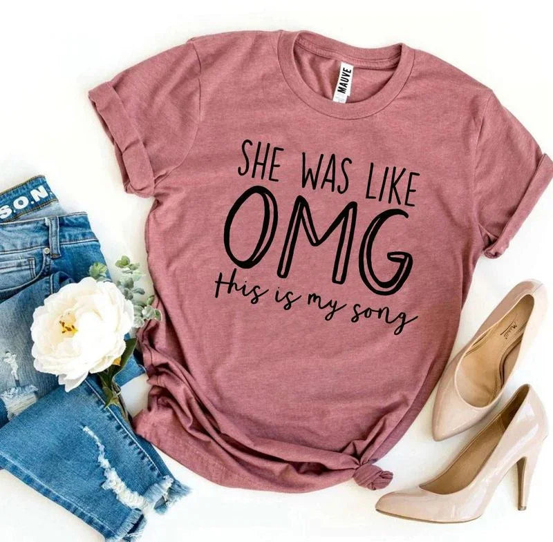 Mauve t-shirt with 'She was like OMG this is my song' text, paired with ripped jeans and nude heels.