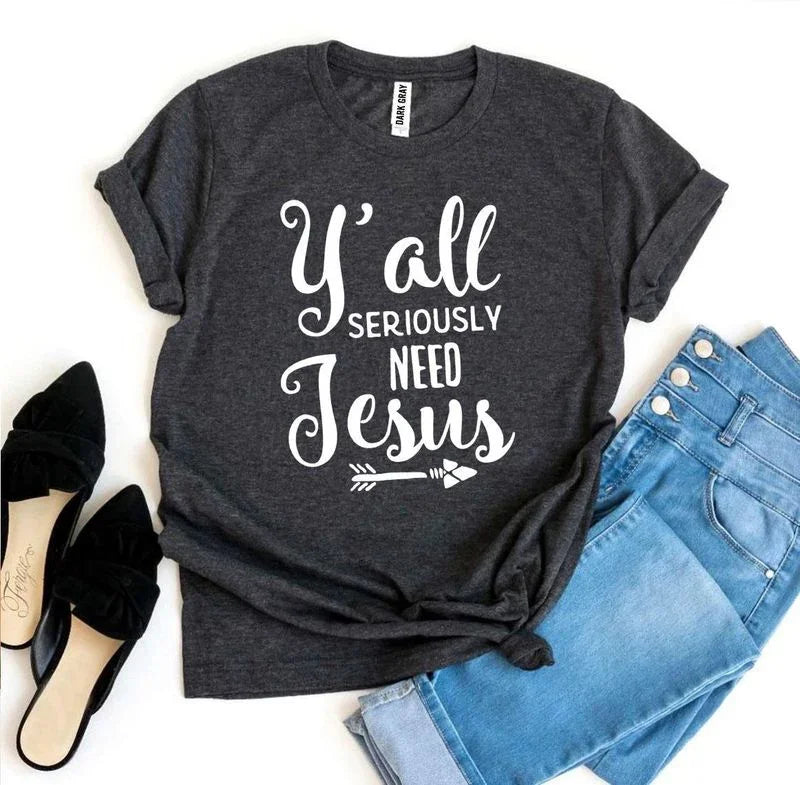 Dark gray graphic t-shirt with 'Y'all Seriously Need Jesus' text, jeans, and black shoes