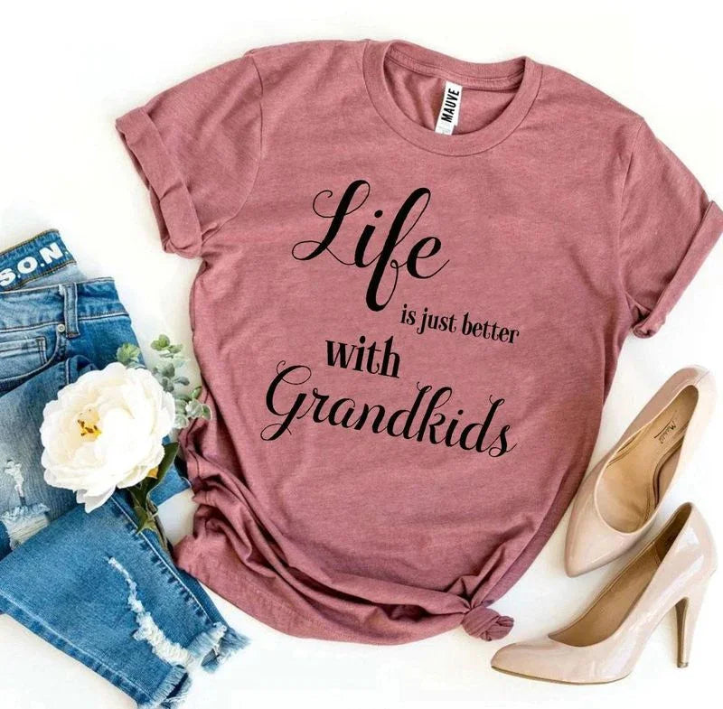 Pink graphic tee with 'Life is just better with Grandkids' text, paired with jeans and heels