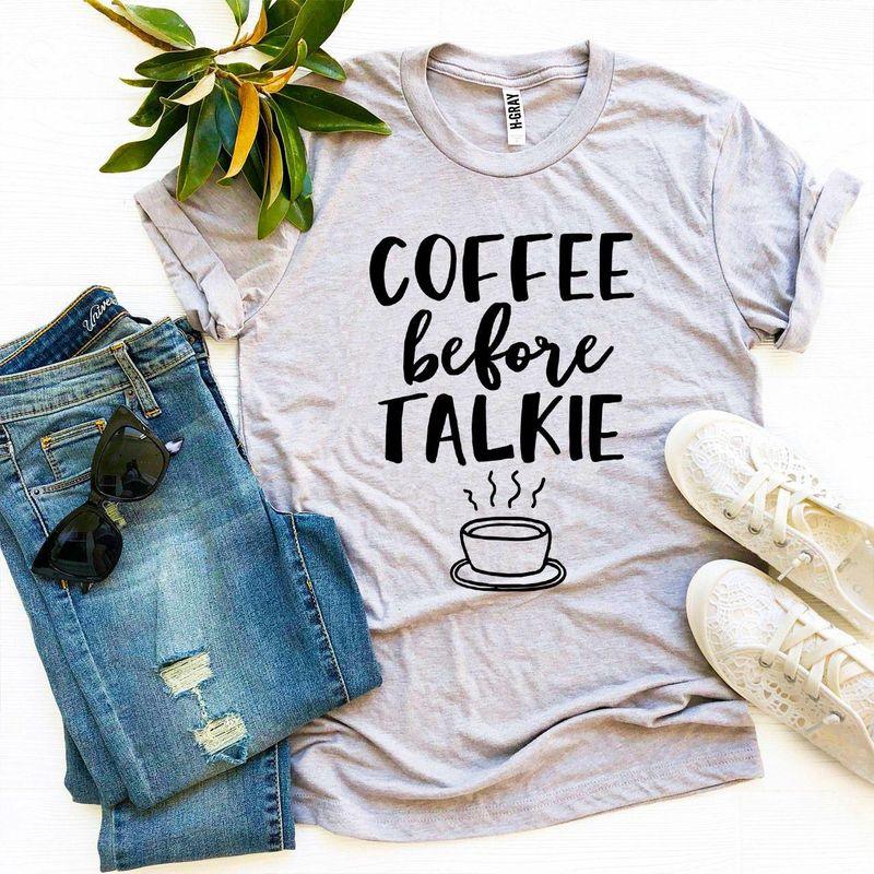 Gray graphic tee with 'Coffee Before Talkie' text, jeans, white sneakers, sunglasses, and plant.