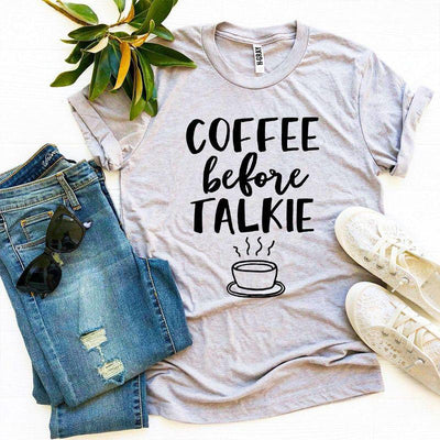 Gray graphic tee with 'Coffee Before Talkie' text, jeans, white sneakers, sunglasses, and plant.