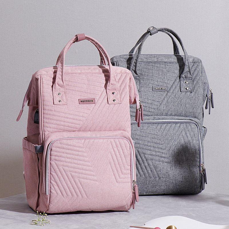 Pink and gray quilted backpacks with top handles on a light textured surface